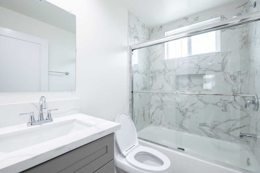a white bathroom with a shower toilet and sink