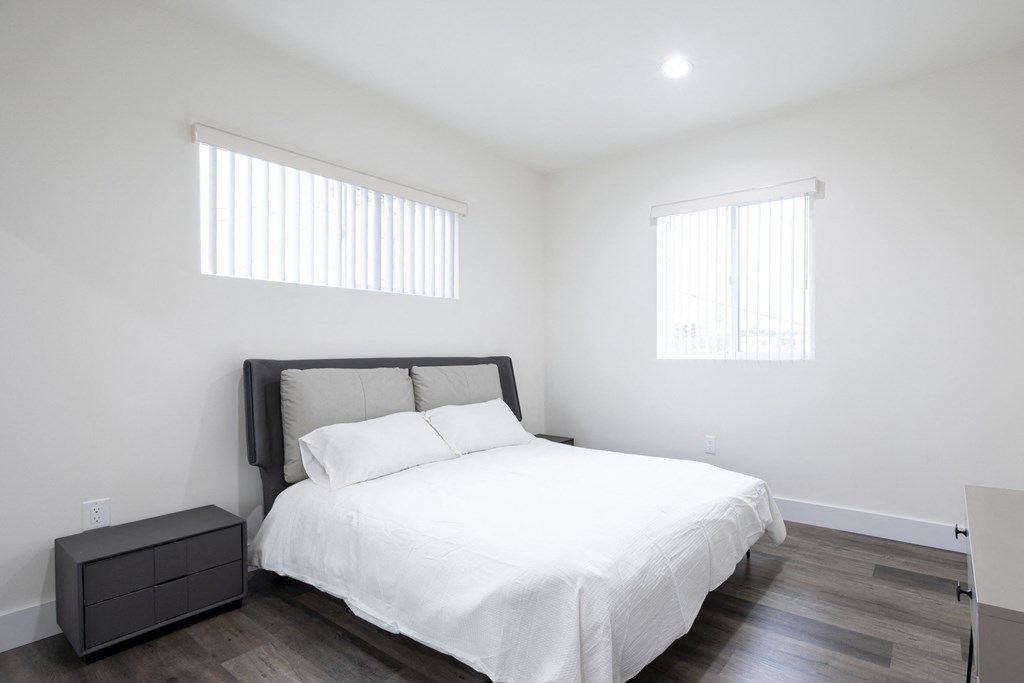 a white bedroom with a white bed and two windows