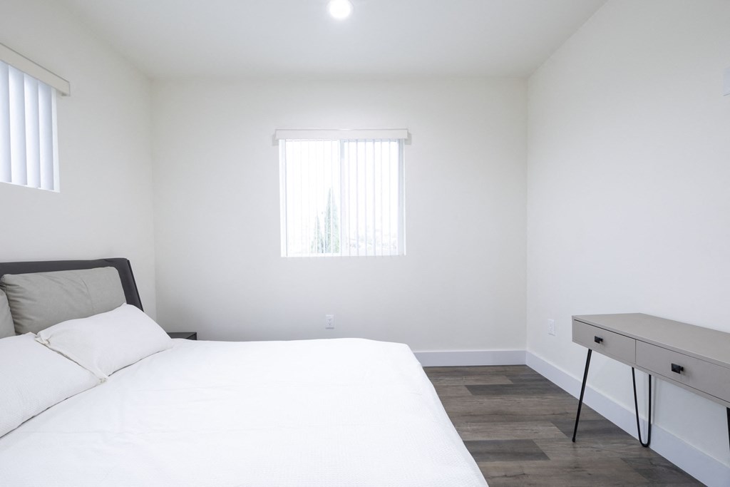 a bedroom with a bed and a desk and a window