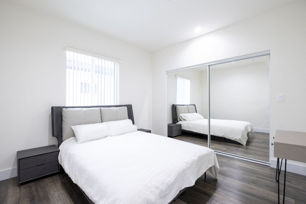 a bedroom with a large white bed and a mirror