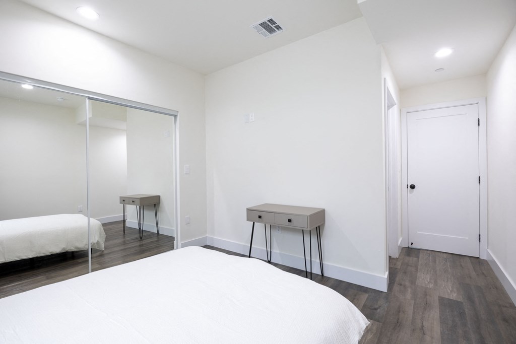 a white bedroom with a white bed and a mirrored closet