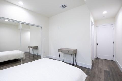 a white bedroom with a white bed and a mirrored closet