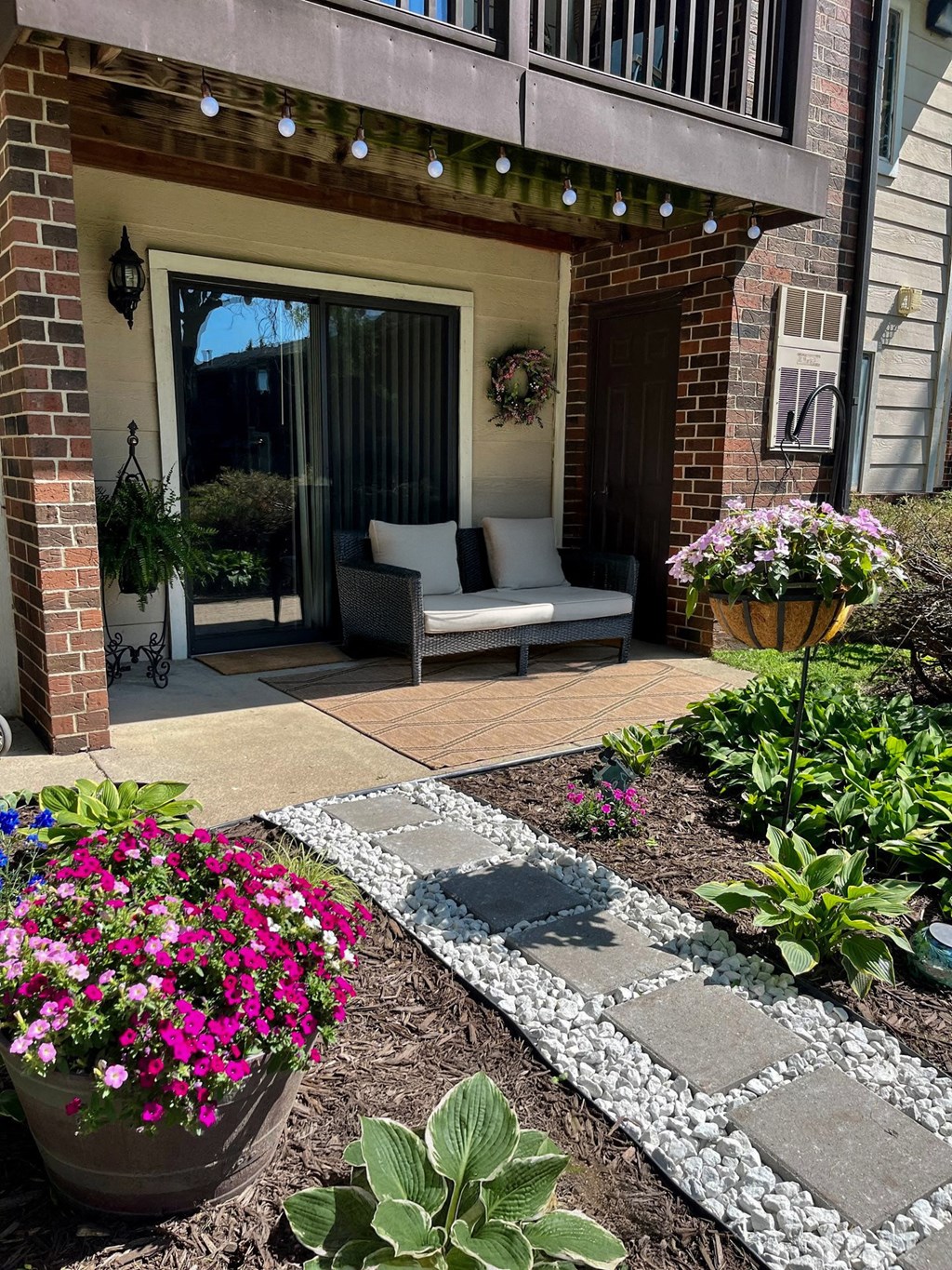 A patio with a couch and a table with a flower pot on the left and a flower pot on the right.