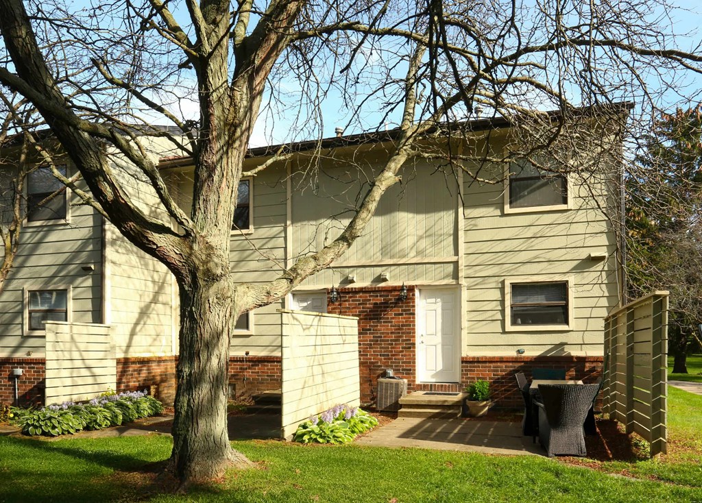 A house with a white door and a tree in front.