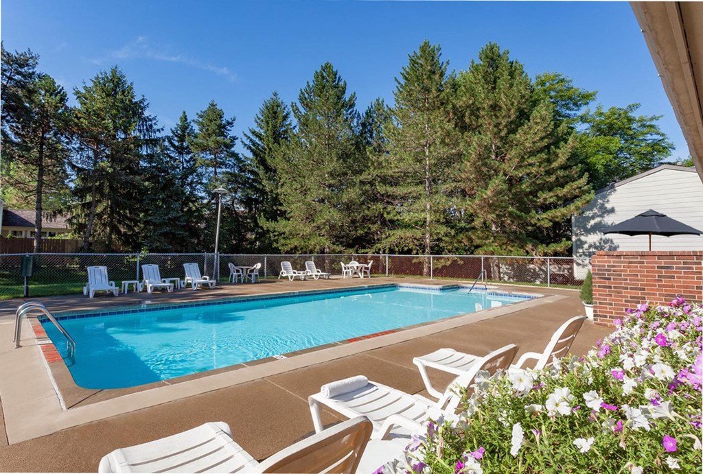A pool surrounded by trees and chairs.