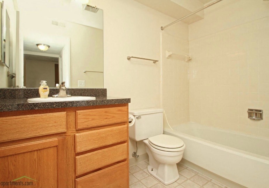 A white toilet sits next to a white bathtub in a bathroom.