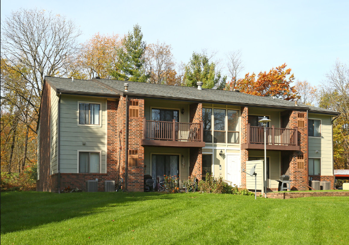 A large brick building with a balcony and a green lawn in front.
