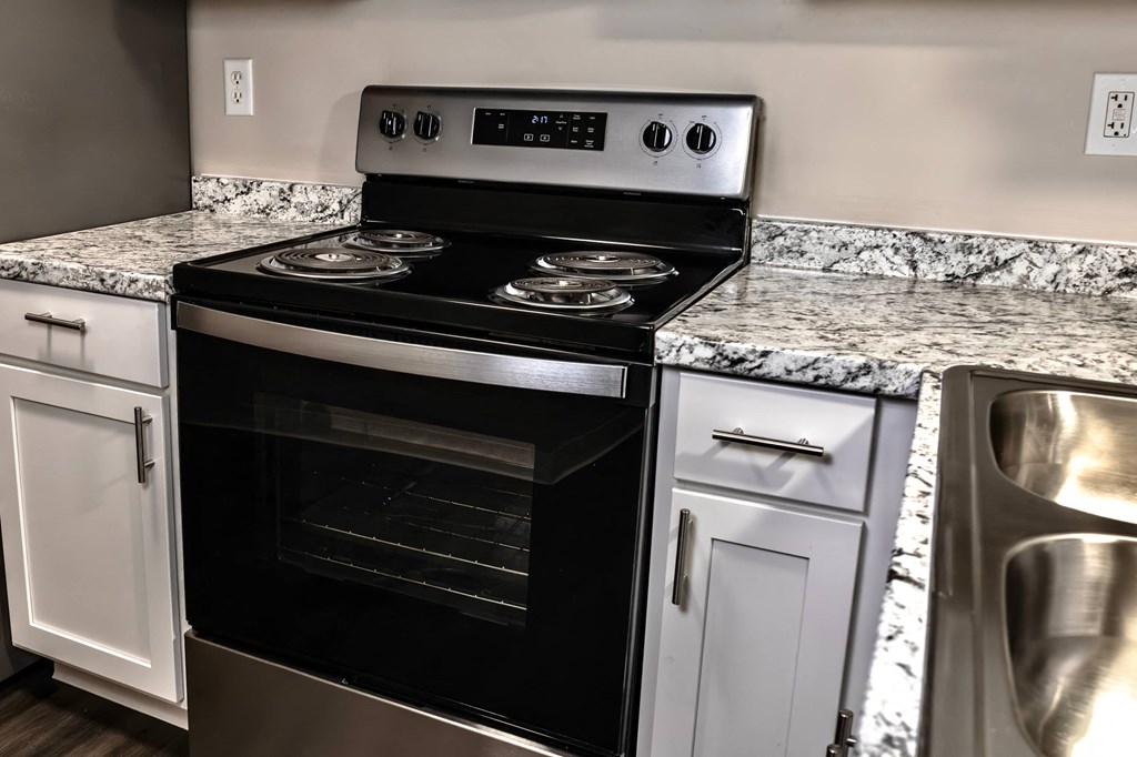 A modern kitchen with a black stove top oven and white cabinets.