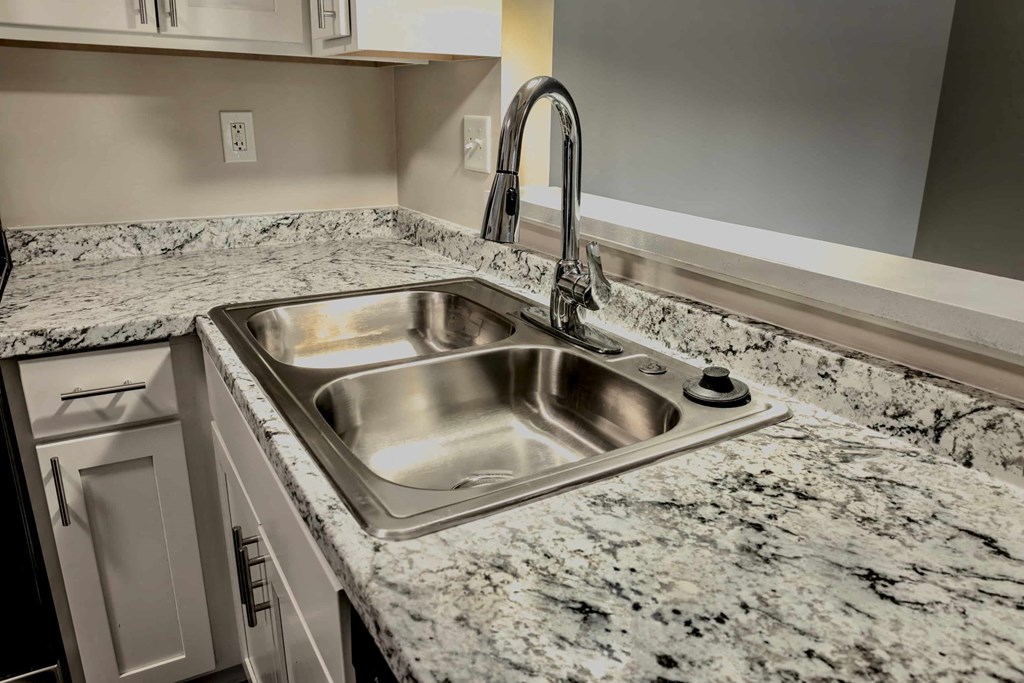 A kitchen sink with a granite countertop and a faucet.