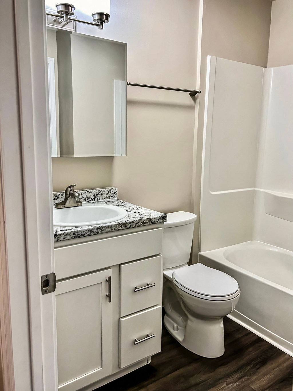 A white toilet is in a bathroom with a sink and mirror.