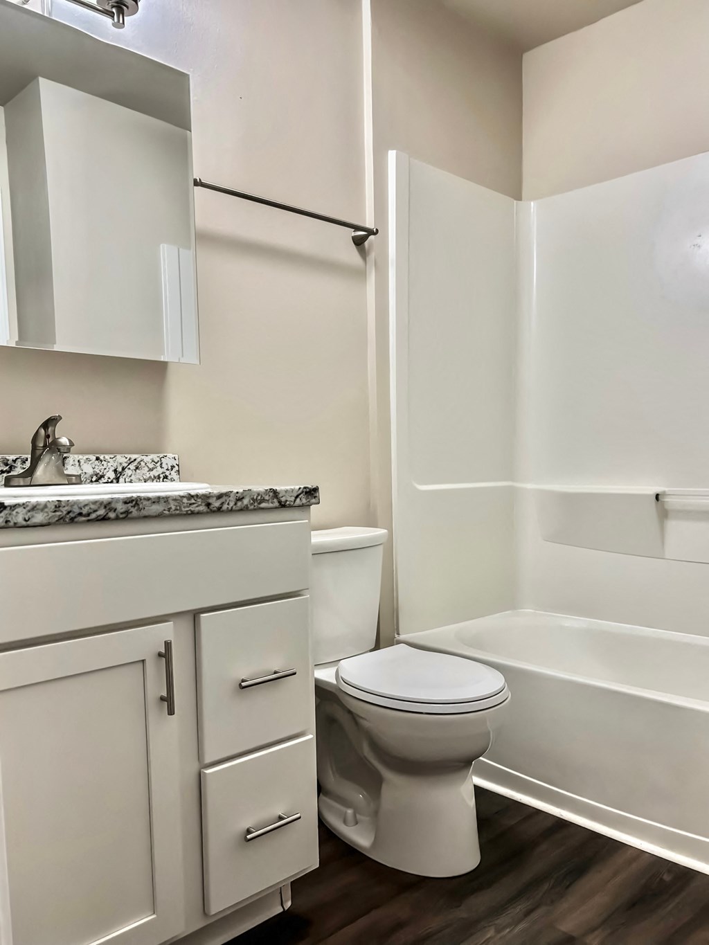 A white toilet sits in a bathroom next to a sink and a bathtub.