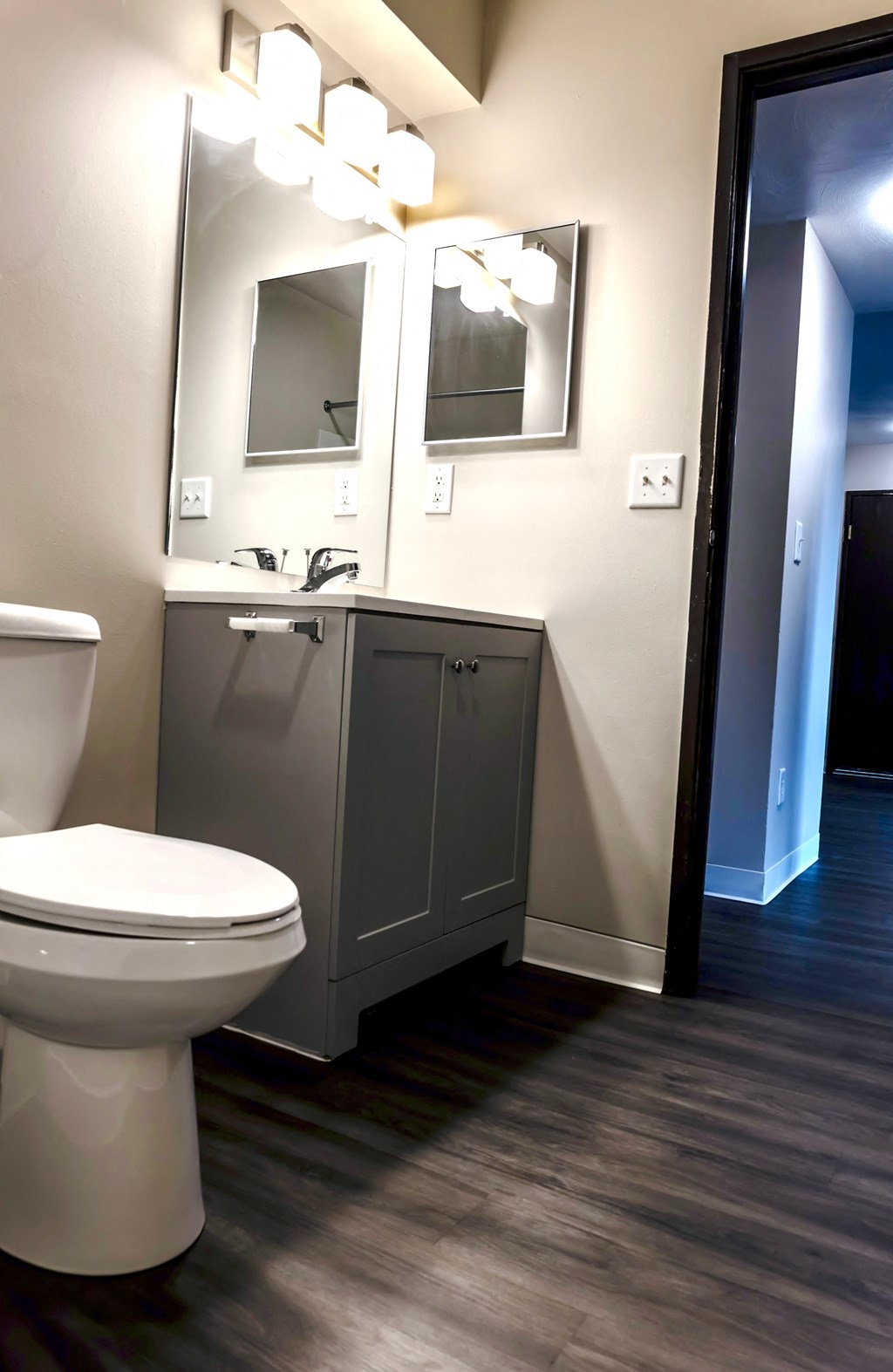 A white toilet sits in a bathroom next to a vanity with a mirror.
