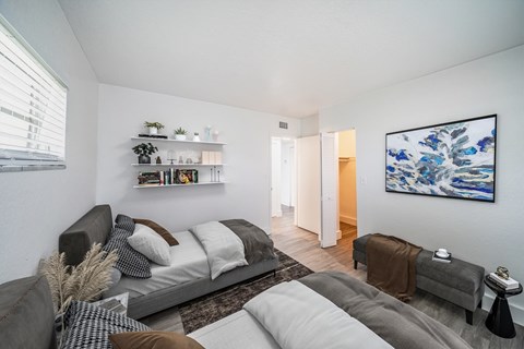 A living room with a grey couch and a large painting on the wall.
