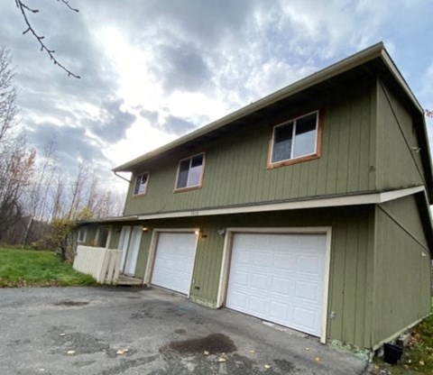 a green house with two white garage doors