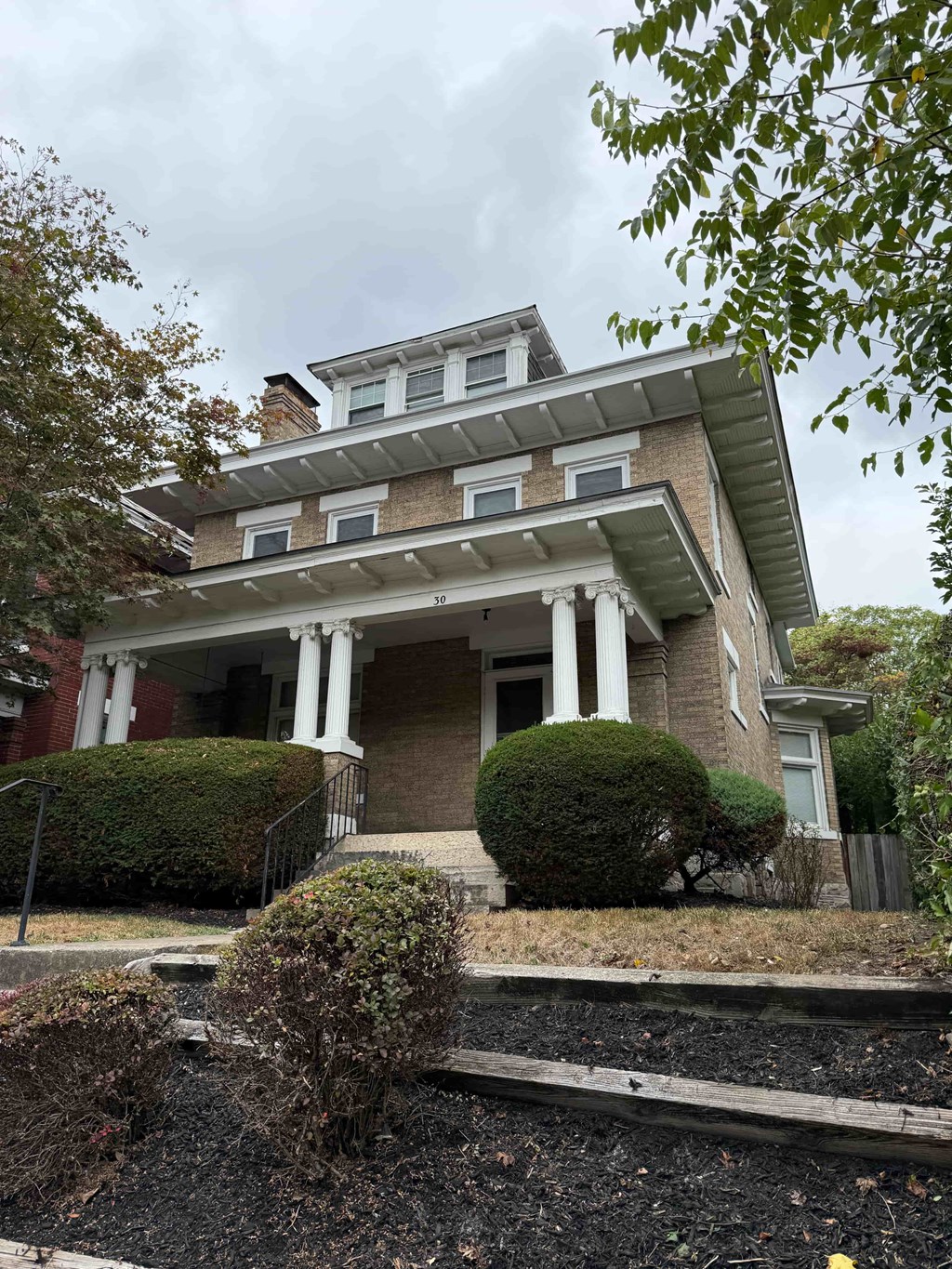 the house has a large porch and a brick building with columns