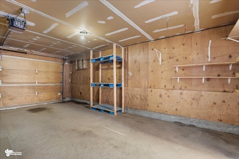 A sparsely furnished room with wooden walls and ceiling, and a concrete floor.