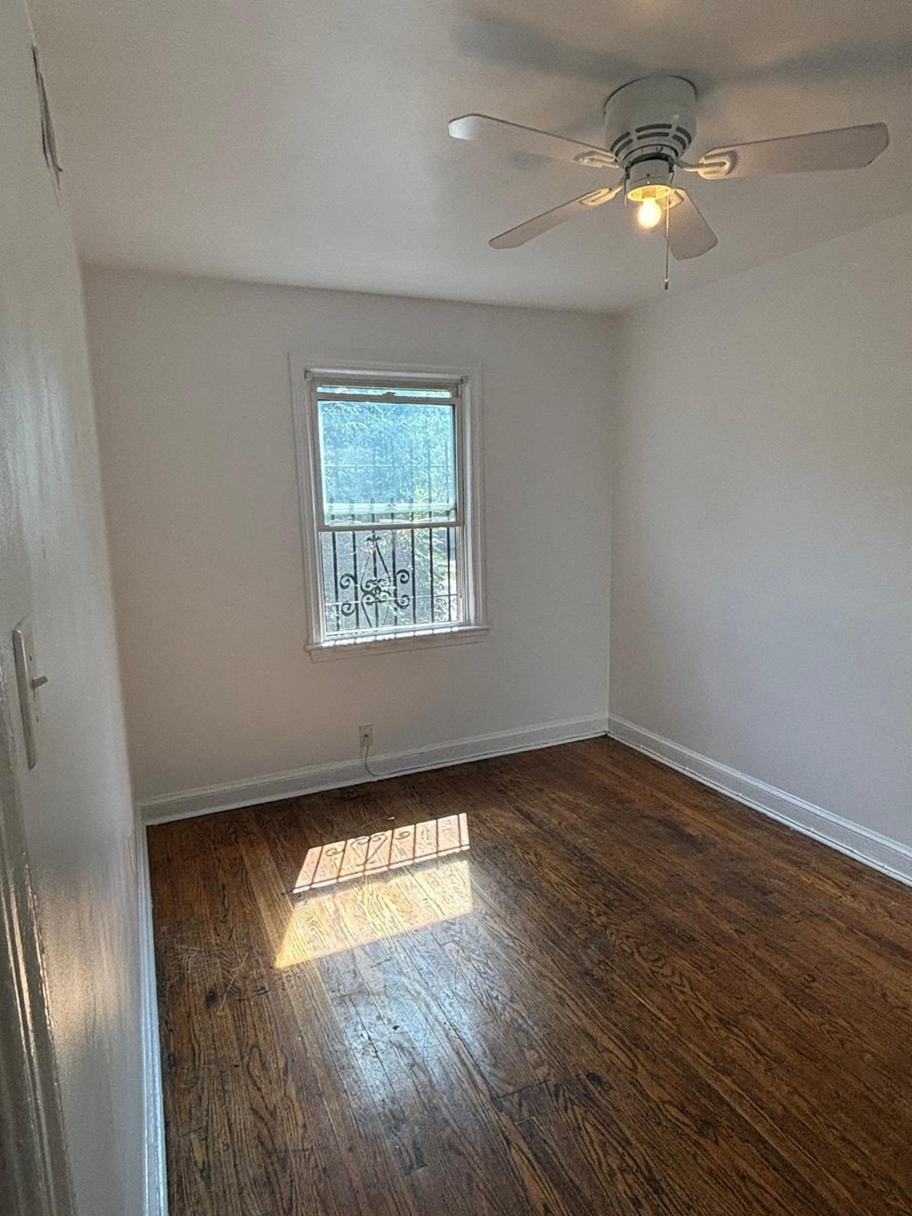 an empty room with a ceiling fan and a window