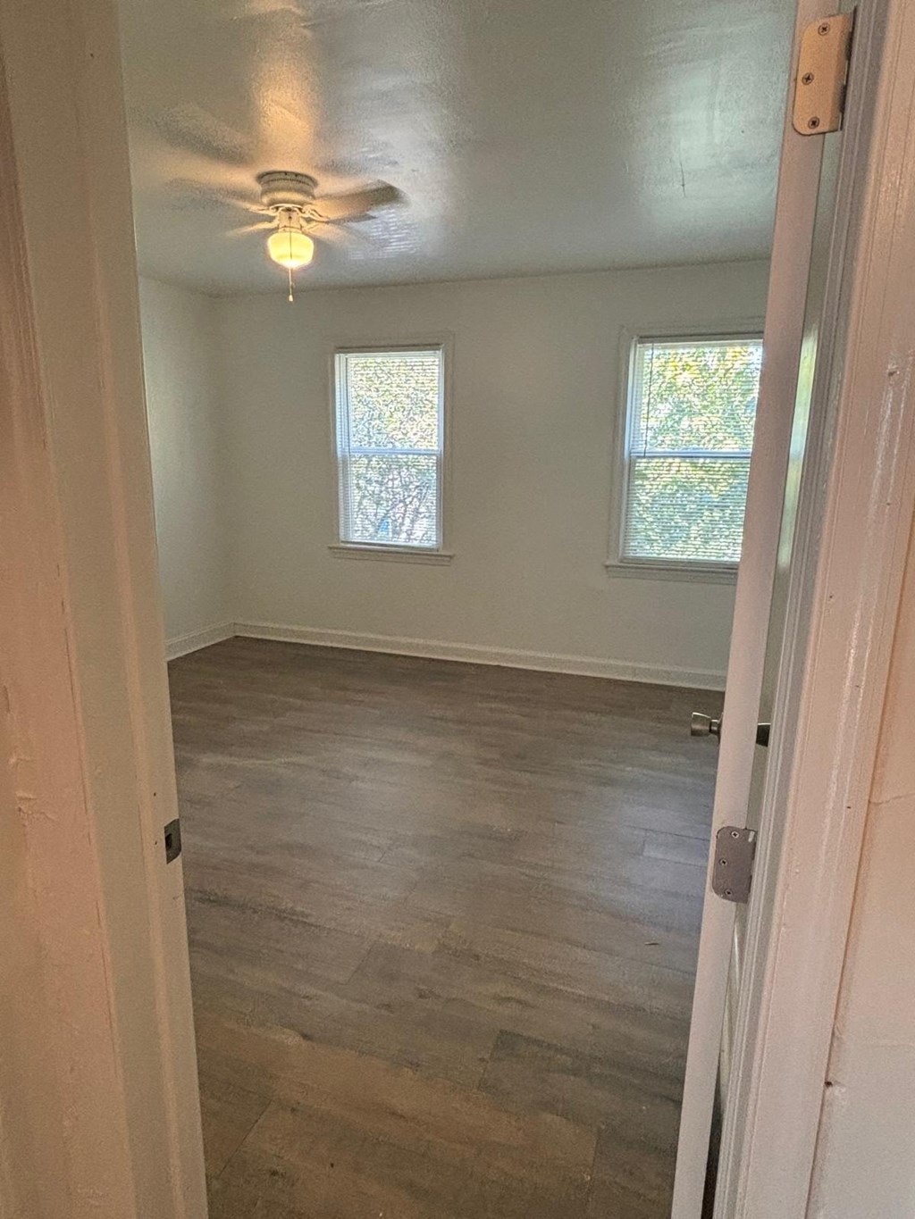an empty room with a ceiling fan and two windows