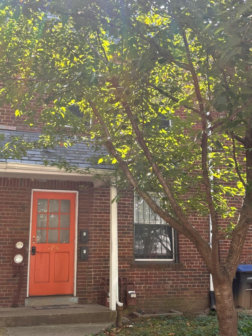 a red door on a brick house with a tree