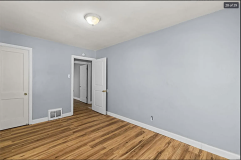 the living room of a renovated house with wood floors and a door to the hallway