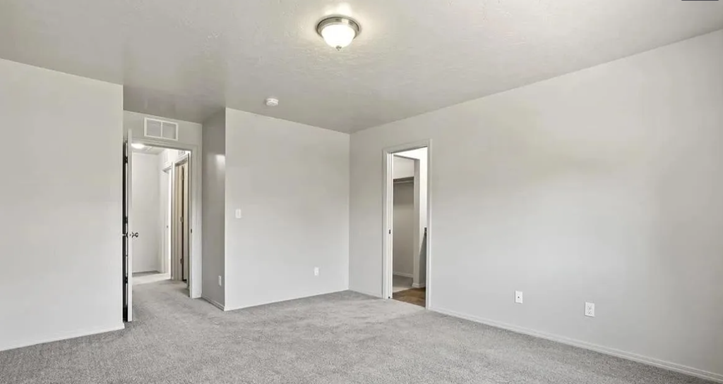 an empty bedroom with white walls and a carpeted floor