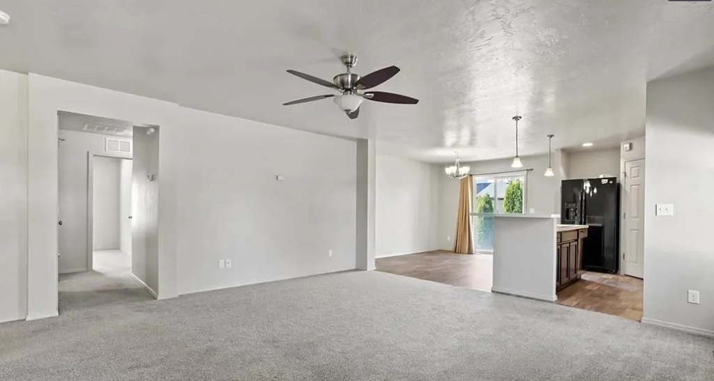 an empty living room with a ceiling fan