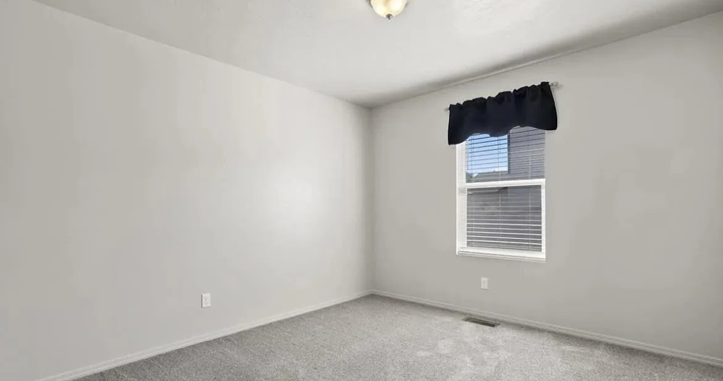 an empty room with a window and a black curtain