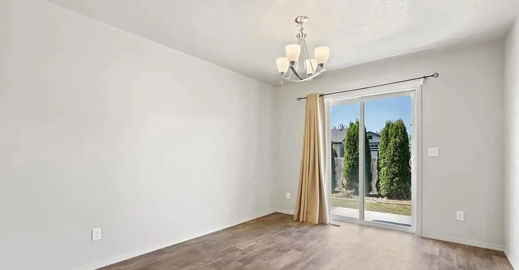 an empty living room with a sliding glass door to a backyard