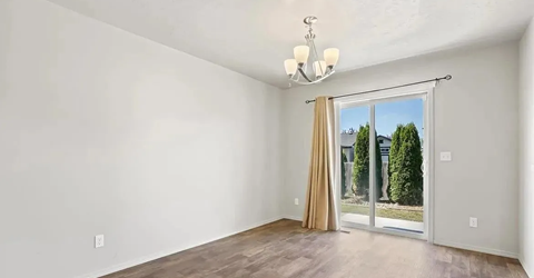 an empty living room with a sliding glass door to a backyard