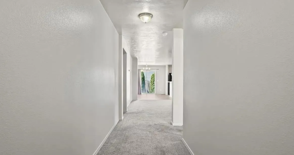 a long hallway with white walls and a ceiling light