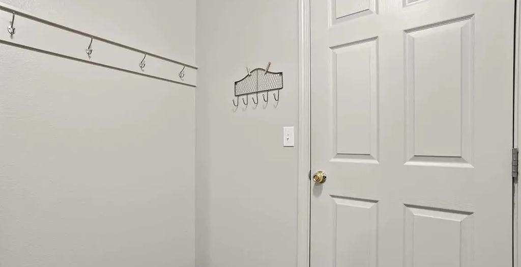 a white door with a clothes rack on the wall