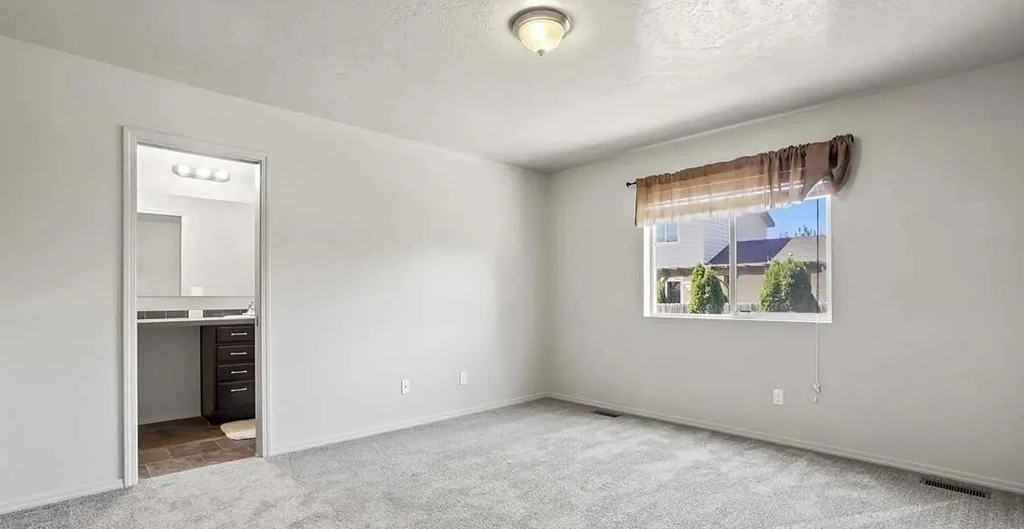 an empty living room with a window and a kitchen