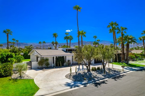 a house with a driveway and palm trees in front of it