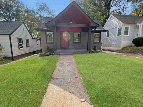 the front of a house with a walkway and lawn