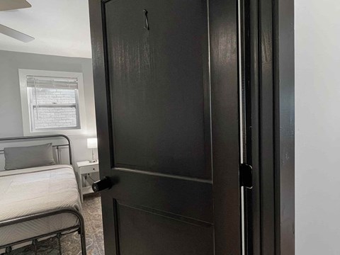 the door is open to a bedroom with a bed