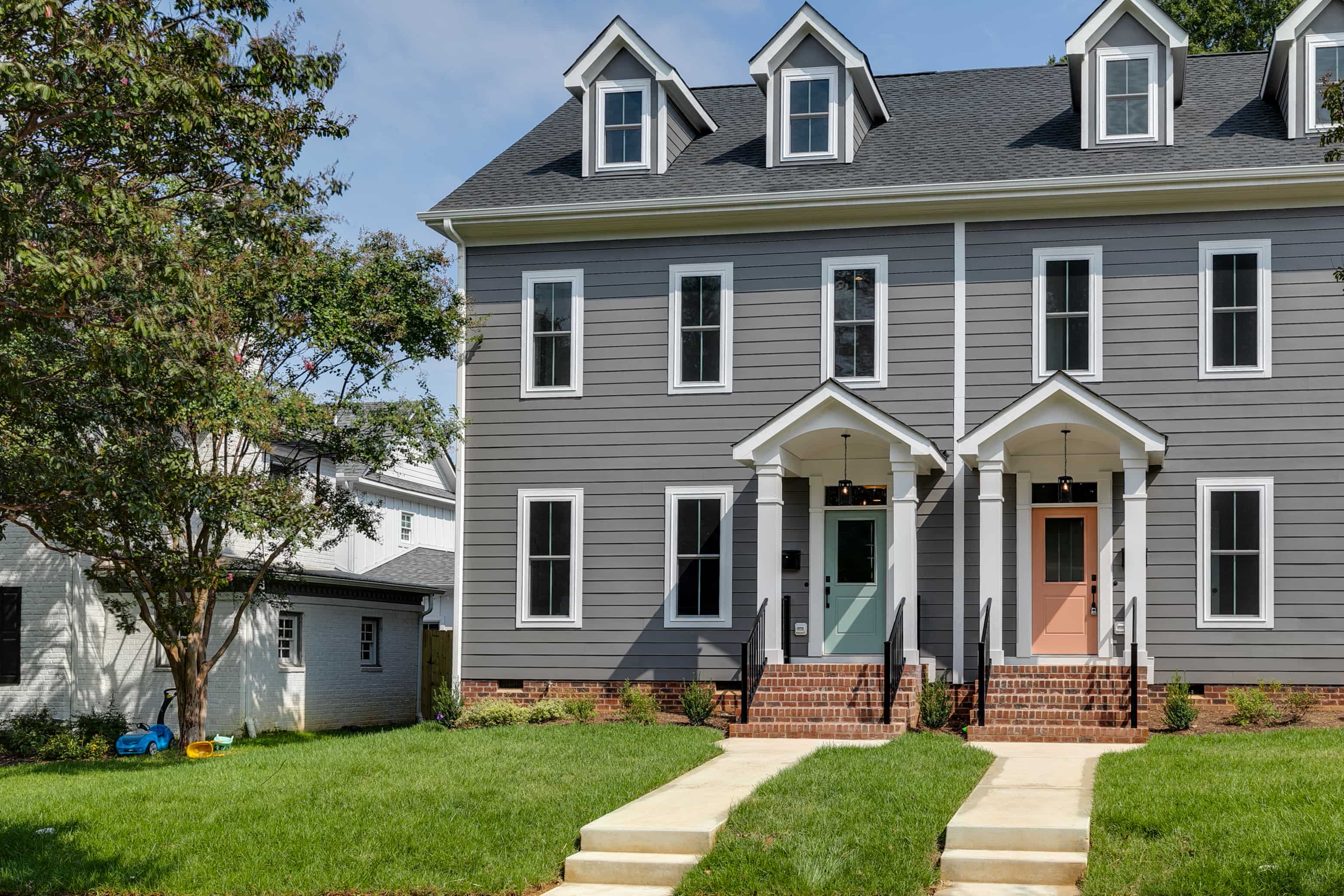 a gray house with a green door and a lawn