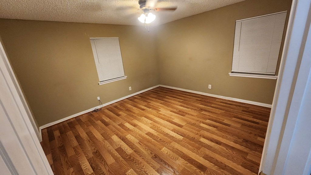 a living room with wood floors and a ceiling fan