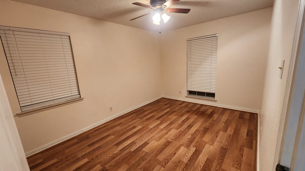 an empty living room with wood floors and a ceiling fan