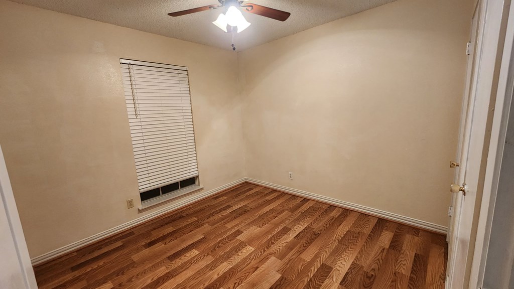 an empty living room with wood floors and a ceiling fan