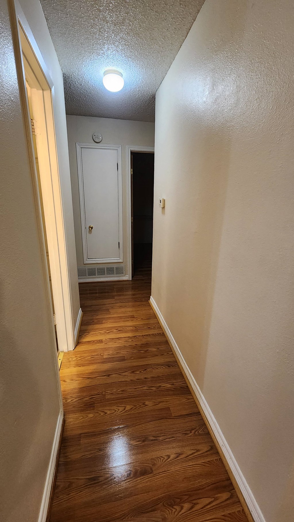 a hallway with wood floors and white walls and a door