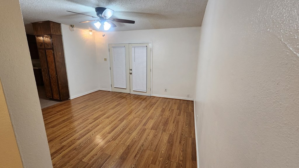 an empty living room with wood flooring and a ceiling fan