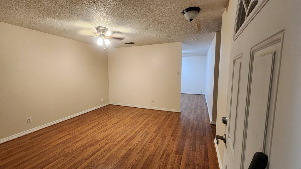 an empty living room with wood flooring and a ceiling fan
