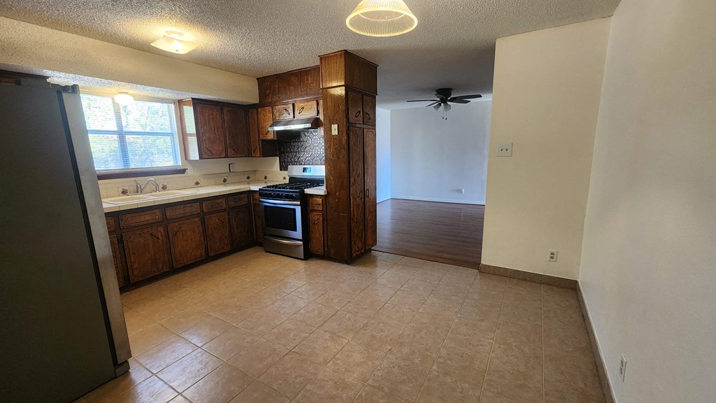 an empty kitchen with wooden cabinets and a ceiling fan