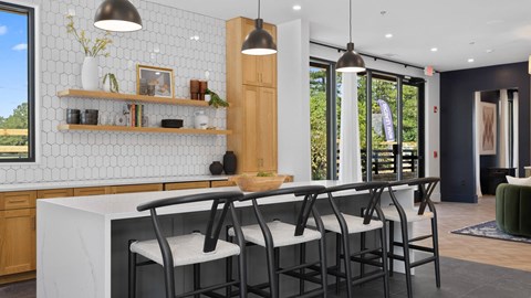 A kitchen with a white counter and black chairs.