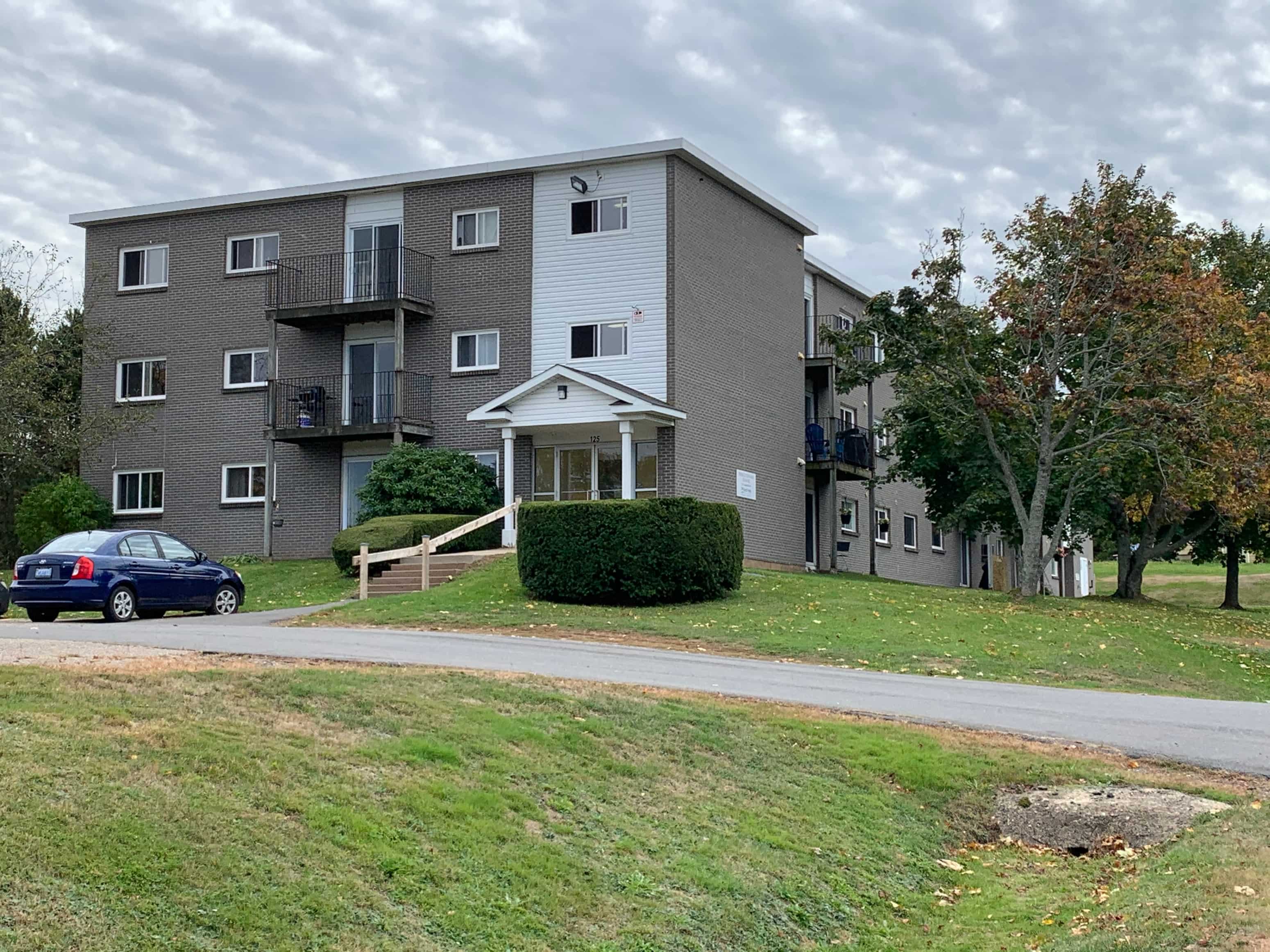 an apartment building with a blue car parked outside