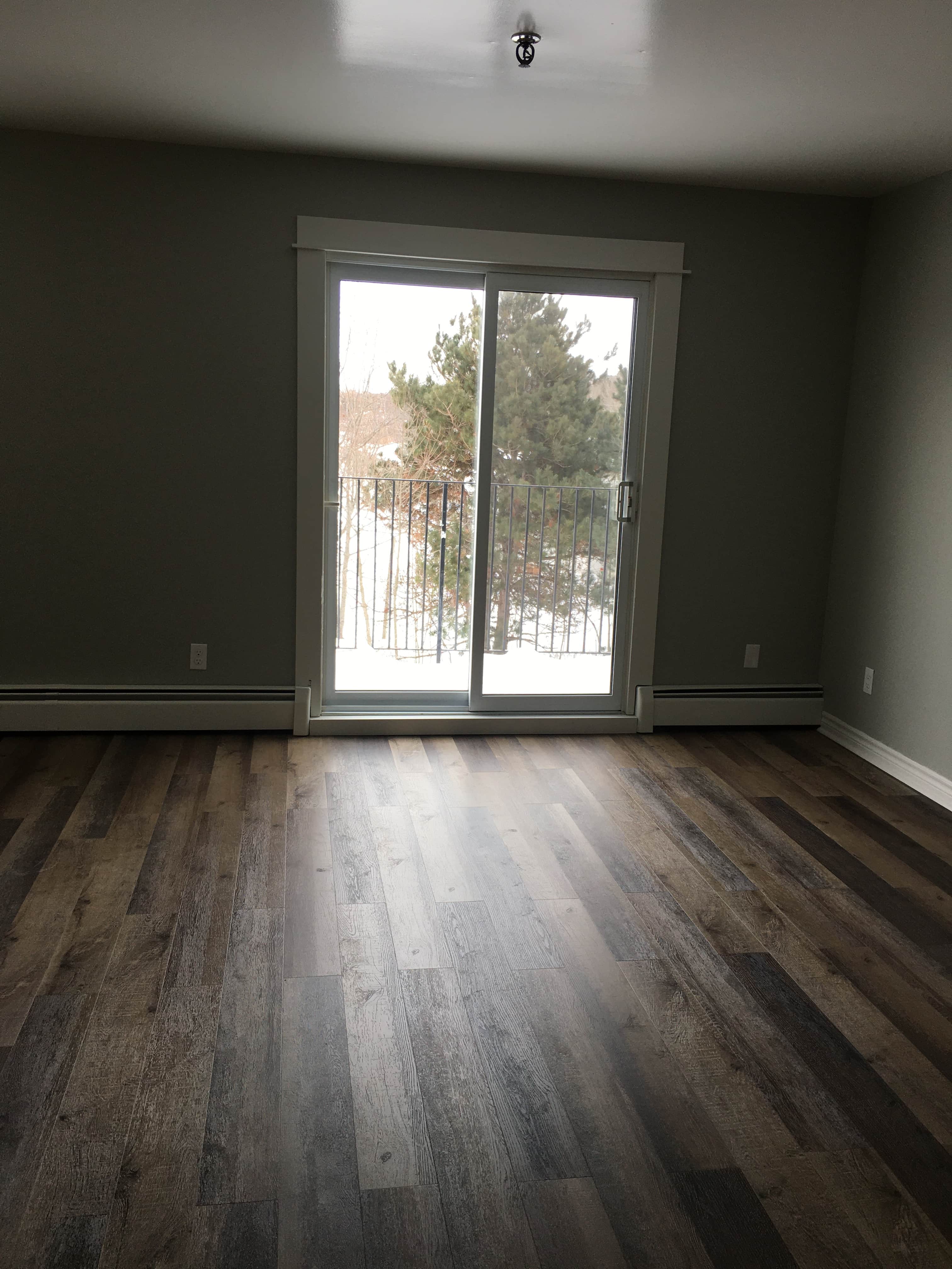 an empty living room with a door to a balcony