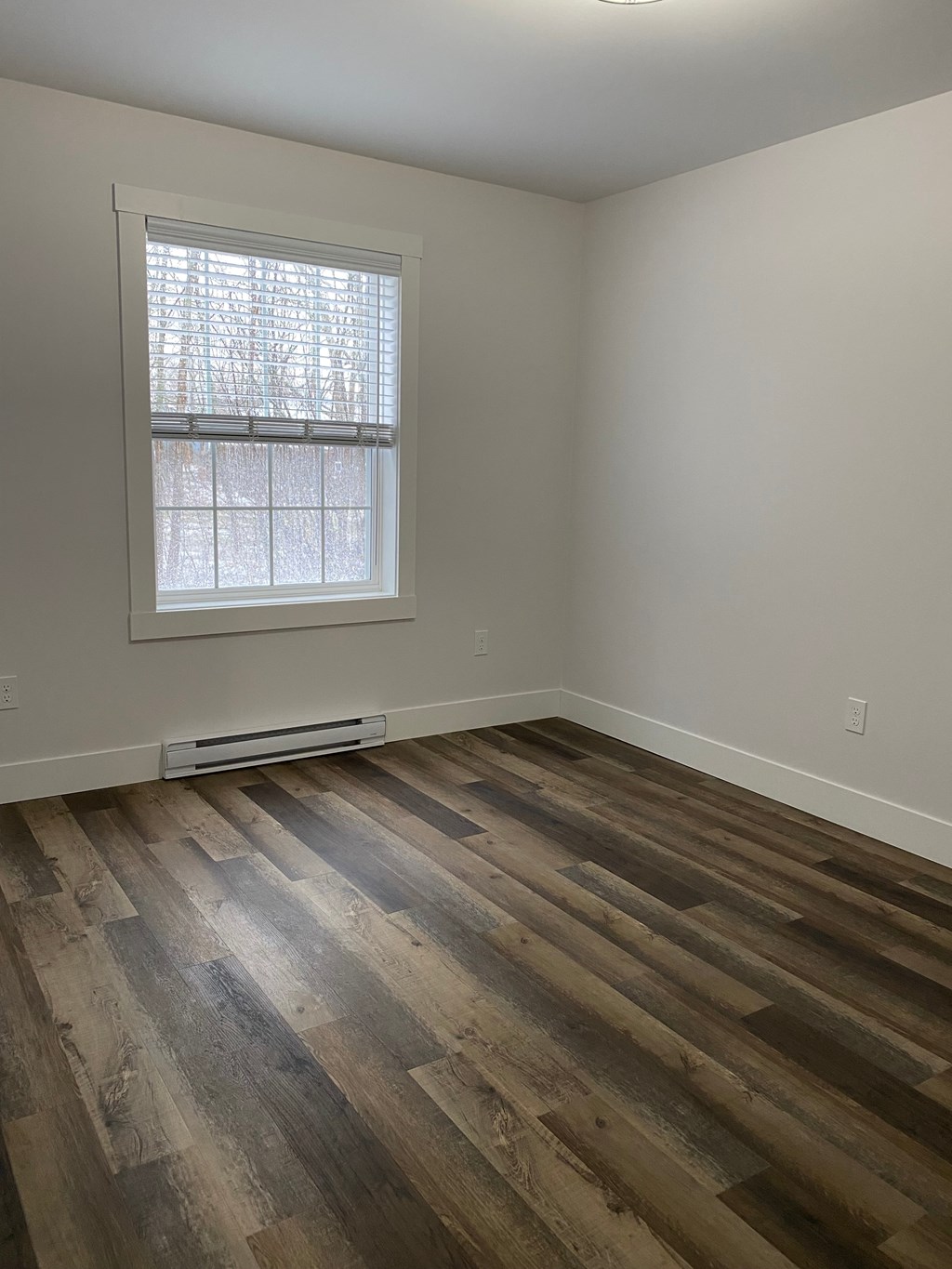 an empty room with wooden floors and a window
