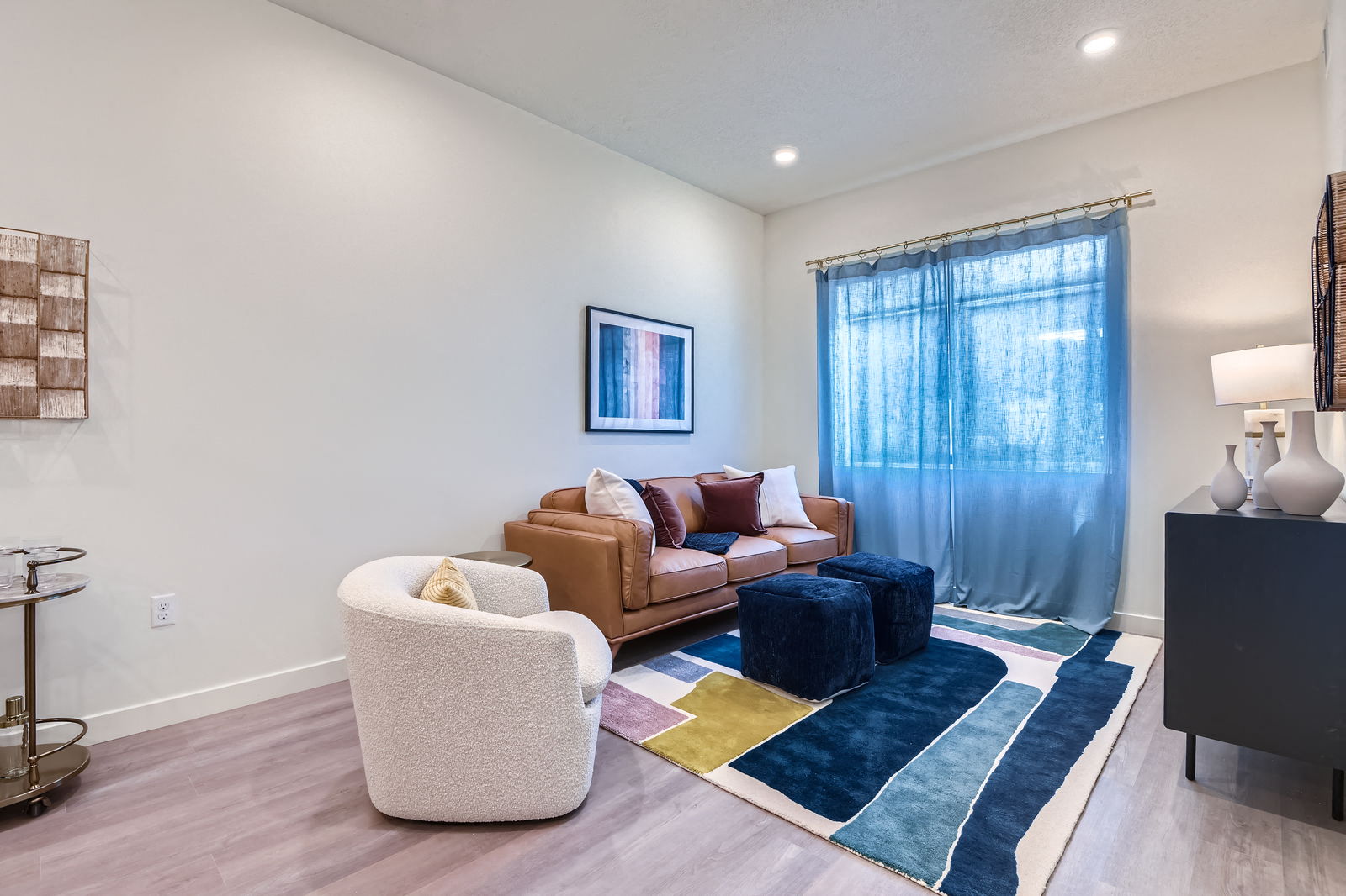 A living room with a brown couch, a white chair, and a blue rug.
