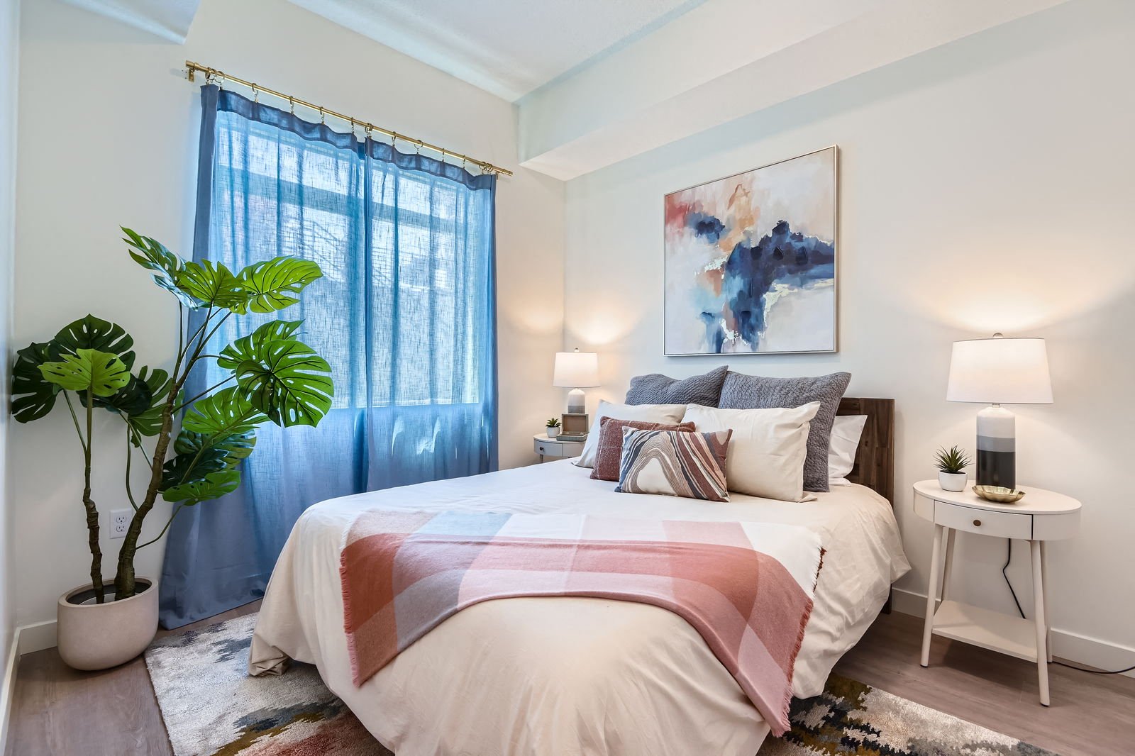 A bedroom with a large bed and a potted plant.