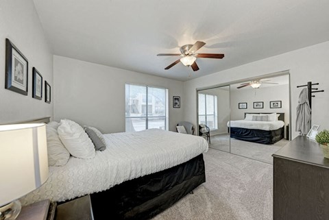 A bedroom with a large bed and a ceiling fan.